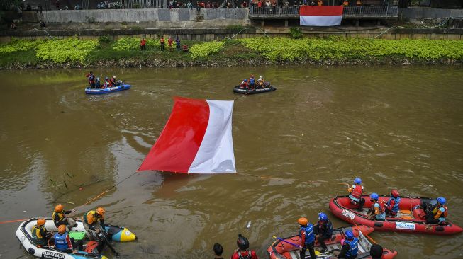 Gabungan relawan rescue membentangkan bendera Merah Putih ukuran 10x5 meter di Kali Ciliwung, Jakarta, Minggu (22/8/2021). [ANTARA FOTO/Galih Pradipta]