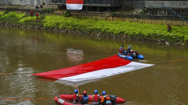 Gabungan relawan rescue membentangkan bendera Merah Putih ukuran 10x5 meter di Kali Ciliwung, Jakarta, Minggu (22/8/2021). [ANTARA FOTO/Galih Pradipta]