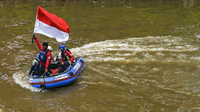 Gabungan relawan rescue mengibarkan bendera Merah Putih di Kali Ciliwung, Jakarta, Minggu (22/8/2021).