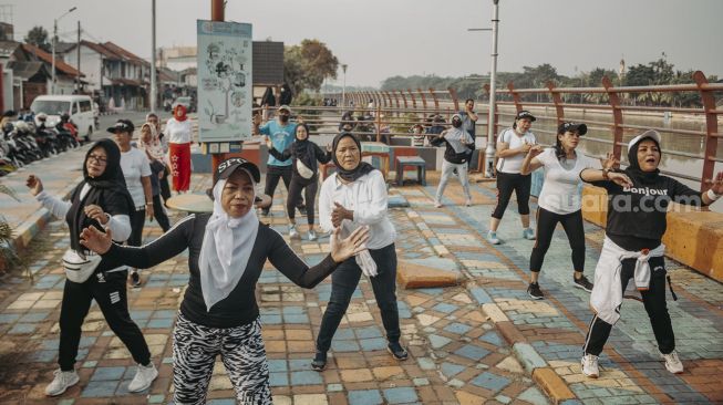 Sejumlah warga berolahraga di pinggir Sungai Cisadane, Kota Tangerang, Banten, Minggu (22/8/2021). [Suara.com/Hilal Rauda Fiqry]