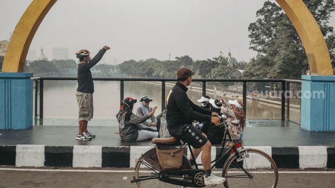 Sejumlah warga berfoto di Jembatan Gerendeng, Kota Tangerang, Banten, Minggu (22/8/2021). [Suara.com/Hilal Rauda Fiqry]