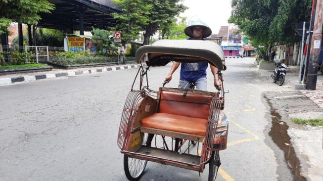 Pardi, pengayuh becak asal Bantul, DIY tengah melintas di sekitar Taman Parkir Ngabean,  Minggu (22/8/2021). [Muhammad Ilham Baktora / SuaraJogja.id]