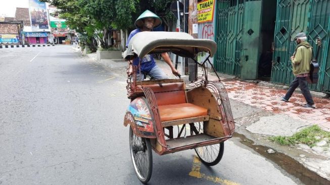 Pardi, pengayuh becak asal Bantul, DIY tengah melintas di sekitar Taman Parkir Ngabean,  Minggu (22/8/2021). [Muhammad Ilham Baktora / SuaraJogja.id]