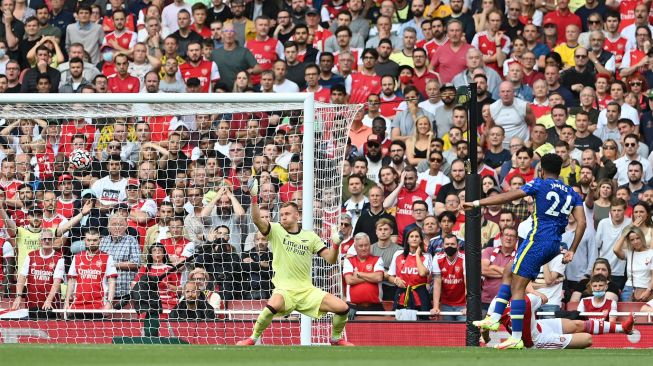 Bek Chelsea Reece James (kanan) menembak melewati kiper Arsenal Bernd Leno (C) untuk mencetak gol kedua timnya selama pertandingan sepak bola Liga Premier Inggris antara Arsenal melawan Chelsea di Emirates Stadium yang rampung Senin (23/8/2021) dini hari WIB. JUSTIN TALLIS / AFP
