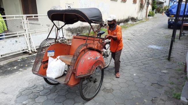 Suratman, pengayuh becak asal Jogja ketika mendorong becak miliknya untuk kembali mencari penumpang di sekitar Jalan Bhayangkara, Kota Jogja,  Minggu (22/8/2021). [Muhammad Ilham Baktora / SuaraJogja.id]