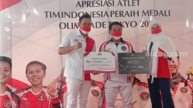 Gilang Widya Pramana (kiri) memberikan hadiah kepada peraih medali di ajang Olimpiade Tokyo 2020. [Yuliani/Suara.com]