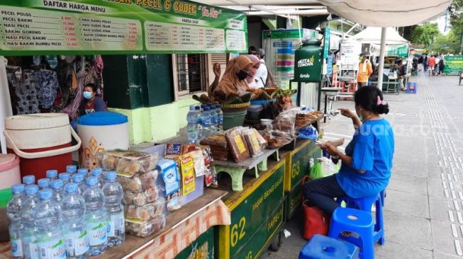 Pedagang di depan Pasar Beringharjo melayani pembeli di Malioboro, Kota Jogja, Minggu (22/8/2021). - (SuaraJogja.id/Muhammad Ilham Baktora)