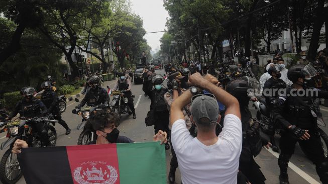 Petugas kepolisian membubarkan paksa pengungsi Afghanistan yang menggelar aksi unjuk rasa di depan Gedung UNHCR, Kebon Sirih, Jakarta, Selasa (24/8/2021). [Suara.com/Angga Budhiyanto]