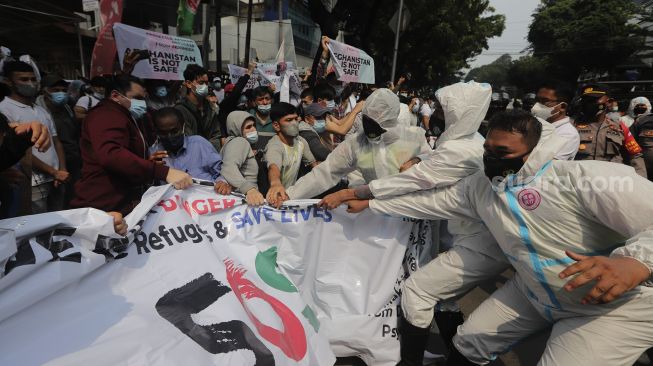 Petugas kepolisian membubarkan paksa pengungsi Afghanistan yang menggelar aksi unjuk rasa di depan Gedung UNHCR, Kebon Sirih, Jakarta, Selasa (24/8/2021). [Suara.com/Angga Budhiyanto]