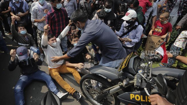 Pengungsi Afghanistan mencoba bertahan saat dibubarkan paksa oleh polisi di depan Gedung UNHCR, Kebon Sirih, Jakarta, Selasa (24/8/2021). [Suara.com/Angga Budhiyanto]