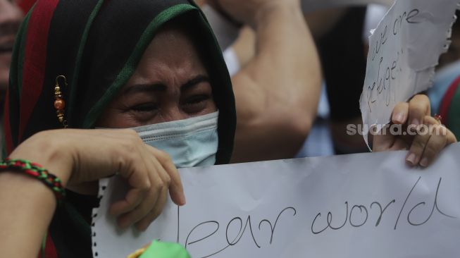 Seorang pengungsi Afghanistan menangis saat menggelar aksi unjuk rasa di depan Gedung UNHCR, Kebon Sirih, Jakarta, Selasa (24/8/2021). [Suara.com/Angga Budhiyanto]
