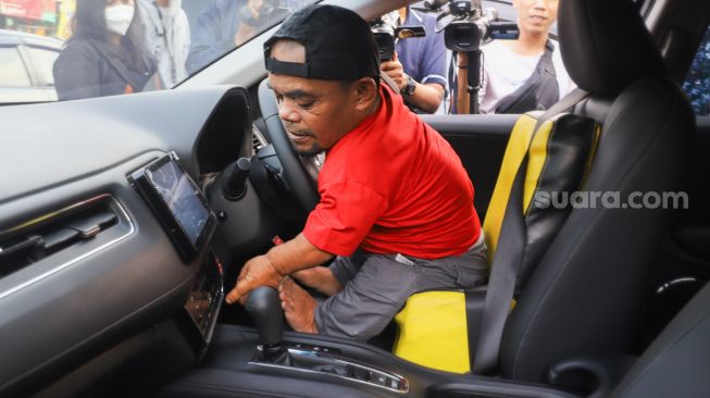 Komedian Ucok Baba mencoba mobil barunya saat ditemui di Cafenya di Kawasan Cipayung, Depok, Jawa Barat, Rabu (25/11/2021). [Suara.com/Alfian Winanto]