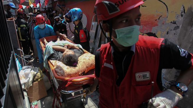 Petugas mengevakuasi korban dari rumah yang lantai duanya ambruk di Jalan Tambaksari Selatan IV, Surabaya, Jawa Timur, Rabu (25/8/2021).  ANTARA FOTO/Didik Suhartono