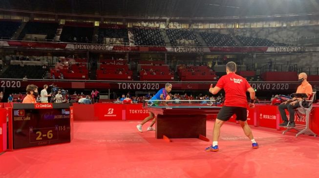 Atlet para-tenis meja Indonesia, David Jacobs (kiri) saat menghadapi Luka Bakic asal Montenegro dalam matchday pertama babak penyisihan Grup B kelas 10 putra Paralimpiade Tokyo 2020 di Tokyo Metropolitan Gymnasium, Rabu (25/8/2021). [Dok. NPC Indonesia]