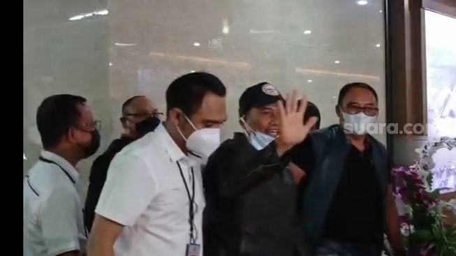 Muhammad Kece melambaikan tangan saat digelandang ke Bareskrim Polri, Jakarta. (Suara.com/M Yasir)