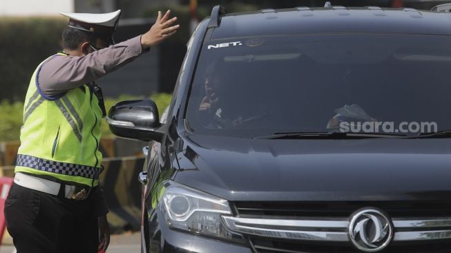 Polisi mengatur lalu lintas kendaraan di pos penerapan ganjil genap di kawasan Bundaran Senayan, Jakarta, Kamis (26/8/2021). [Suara.com/Angga Budhiyanto]