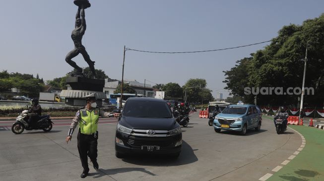 Polisi mengatur lalu lintas kendaraan di pos penerapan ganjil genap di kawasan Bundaran Senayan, Jakarta, Kamis (26/8/2021). [Suara.com/Angga Budhiyanto]