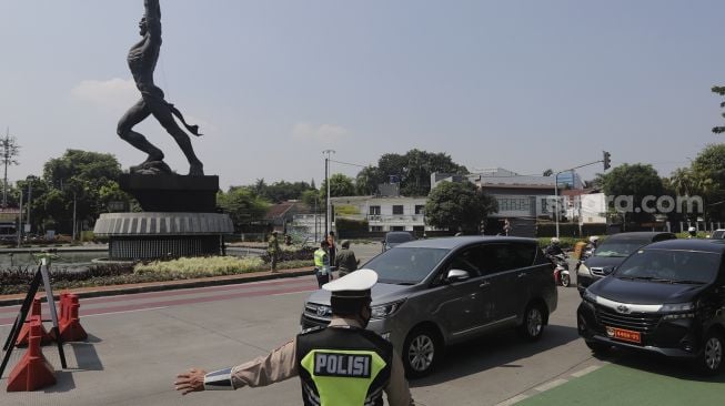 Polisi mengatur lalu lintas kendaraan di pos penerapan ganjil genap di kawasan Bundaran Senayan, Jakarta, Kamis (26/8/2021). [Suara.com/Angga Budhiyanto]