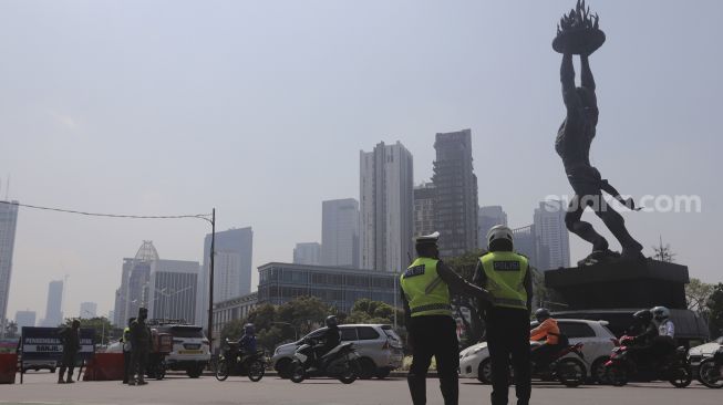 Polisi mengatur lalu lintas kendaraan di pos penerapan ganjil genap di kawasan Bundaran Senayan, Jakarta, Kamis (26/8/2021). [Suara.com/Angga Budhiyanto]