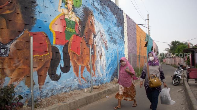 Sejumlah Warga Melintas di depan mural di Kampung Pink Tanah Tinggi Kota Tangerang Jumat 27 Agustus 2021 ( Suara.com/ Hilal Rauda Fiqry)