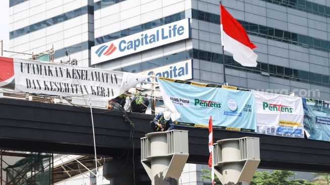 Pekerja menyelesaikan proyek pembangunan Jembatan Penyeberangan Orang (JPO) sekaligus Jembatan Penyeberangan Sepeda (JPS) Karet-Sudirman di Karet Tengsin, Jakarta Pusat, Sabtu (28/8/2021). [Suara.com/Alfian Winanto]