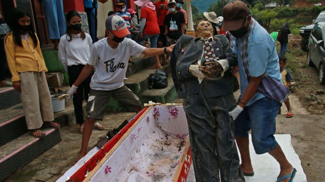 Sejumlah kerabat mengangkat jenazah keluarga untuk dibersihkan saat ritual Manene di Pangala, Kecamatan Rindingallo, Kabupaten Toraja Utara, Sulawesi Selatan, Jumat (27/8/2021). ANTARA FOTO / Sevianto Pakiding
