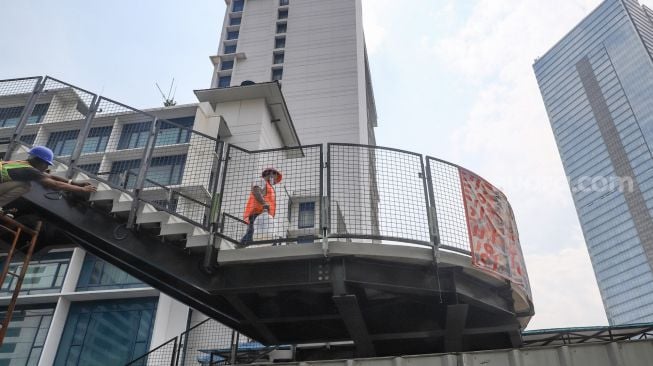 Pekerja menyelesaikan proyek pembangunan Jembatan Penyeberangan Orang (JPO) sekaligus Jembatan Penyeberangan Sepeda (JPS) Karet-Sudirman di Karet Tengsin, Jakarta Pusat, Sabtu (28/8/2021). [Suara.com/Alfian Winanto]