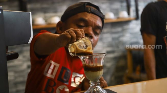 Komedian Ucok Baba meracik kopi spesial buatannya saat ditemui di Cafenya di Kawasan Cipayung, Depok, Jawa Barat, Rabu (25/8/2021). [Suara.com/Alfian Winanto]