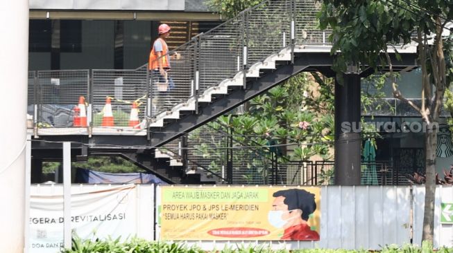 Pekerja menyelesaikan proyek pembangunan Jembatan Penyeberangan Orang (JPO) sekaligus Jembatan Penyeberangan Sepeda (JPS) Karet-Sudirman di Karet Tengsin, Jakarta Pusat, Sabtu (28/8/2021). [Suara.com/Alfian Winanto]