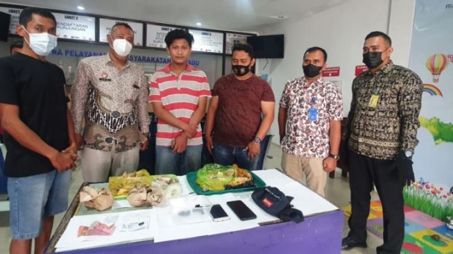 Pengunjung berinisal HA (tengah/tidak bermasker) bersama barang buktinya saat diamankan petugas Rutan di Gresik. [ANTARA/HO-Rutan Kelas IIB Kabupaten Gresik]