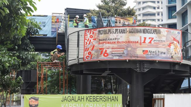 Pekerja menyelesaikan proyek pembangunan Jembatan Penyeberangan Orang (JPO) sekaligus Jembatan Penyeberangan Sepeda (JPS) Karet-Sudirman di Karet Tengsin, Jakarta Pusat, Sabtu (28/8/2021). [Suara.com/Alfian Winanto]