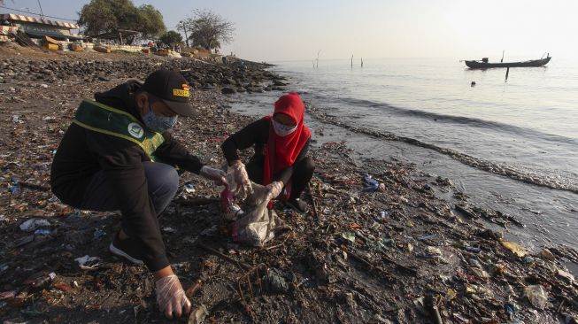 Warga memungut sampah di pinggir pantai kawasan Kedung Cowek, Surabaya, Jawa Timur, Minggu (29/8/2021). [ANTARA FOTO/Didik Suhartono]