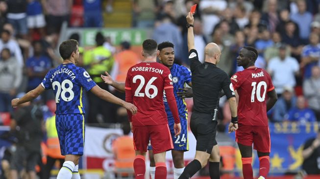 Wasit Anthony Taylor memberikan kartu merah kepada bek Chelsea Reece James (tengah) setelah ia menyentuh bola di kotak penalti selama pertandingan sepak bola Liga Premier Inggris antara Liverpool dan Chelsea di Anfield, Liverpool, Inggris, pada (28/8/2021). [Paul ELLIS / AFP]