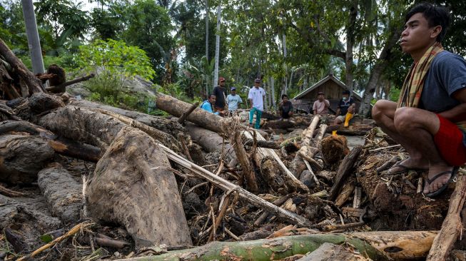 Sejumlah warga berada di antara tumpukan potongan kayu yang terbawa saat terjadi banjir bandang di Desa Rogo, Dolo Selatan, Sigi, Sulawesi Tengah, Senin (30/8/2021). [ANTARA FOTO/Basri Marzuki]