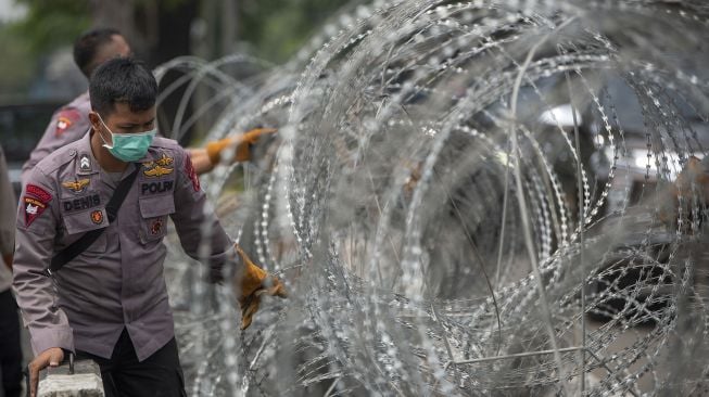 Polisi menata barikade kawat berduri dalam pengamanan sidang putusan banding Rizieq Shihab terkait perkara tes swab RS Ummi Bogor di Pengadilan Tinggi DKI Jakarta, Jakarta, Senin (30/8/2021). [ANTARA FOTO/Aditya Pradana Putra]