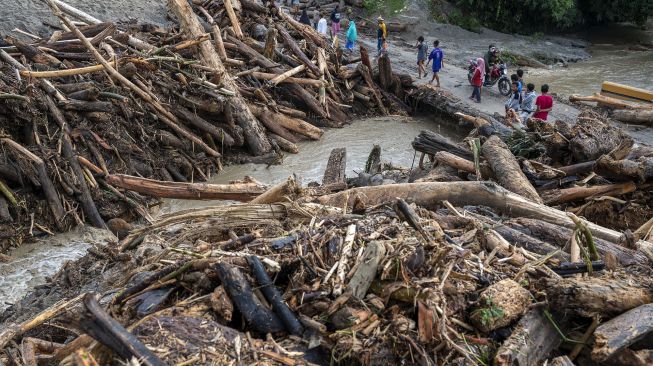 Sejumlah warga berada di antara tumpukan potongan kayu yang terbawa saat terjadi banjir bandang di Desa Rogo, Dolo Selatan, Sigi, Sulawesi Tengah, Senin (30/8/2021). [ANTARA FOTO/Basri Marzuki]