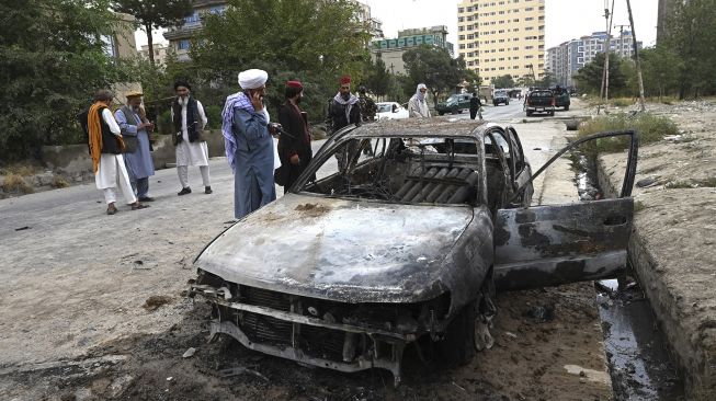 Pejuang Taliban menyelidiki mobil yang rusak setelah beberapa roket ditembakkan di Kabul, Afghanistan, Senin (30/8/2021). [Wakil Kohsar / AFP]