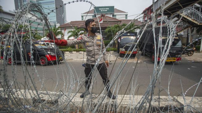 Polisi menata barikade kawat berduri dalam pengamanan sidang putusan banding Rizieq Shihab terkait perkara tes swab RS Ummi Bogor di Pengadilan Tinggi DKI Jakarta, Jakarta, Senin (30/8/2021). [ANTARA FOTO/Aditya Pradana Putra]