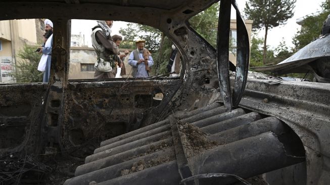 Pejuang Taliban menyelidiki mobil yang rusak setelah beberapa roket ditembakkan di Kabul, Afghanistan, Senin (30/8/2021). [Wakil Kohsar / AFP]