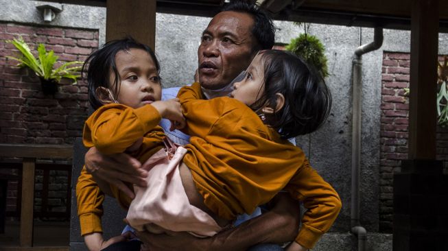 Anak kembar siam Al Putri Dewi Ningsih dan Al Putri Anugrah digendong oleh ayahnya di Bandung, Jawa Barat, Senin (30/8/2021). ANTARA FOTO/Novrian Arbi