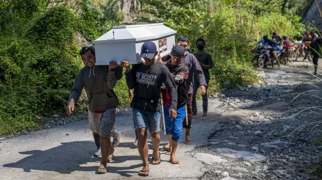 Warga memikul peti jenazah melintasi jalan Trans Palu-Kulawi yang sebagiannya tertimbun material longsoran di Desa Salua, Sigi, Sulawesi Tengah, Selasa (31/8/2021). ANTARA FOTO/Basri Marzuki