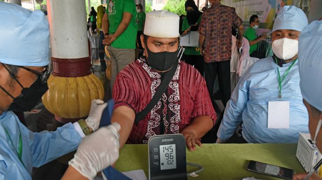 Petugas memeriksa kesehatan Pengasuh Ponpes Al-Hikam KH Tohir Ishaq saat acara Vaksinasi COVID-19 untuk Kiai dan Santri di Mesjid Agung Atsauroh Serang, Banten, Selasa (31/8/2021). ANTARA FOTO/Asep Fathulrahman