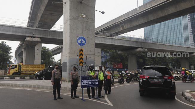 Polisi mengatur lalu lintas kendaraan di pos penerapan ganjil genap di Jalan HR Rasuna Said, Jakarta, Rabu (1/9/2021). [Suara.com/Angga Budhiyanto]