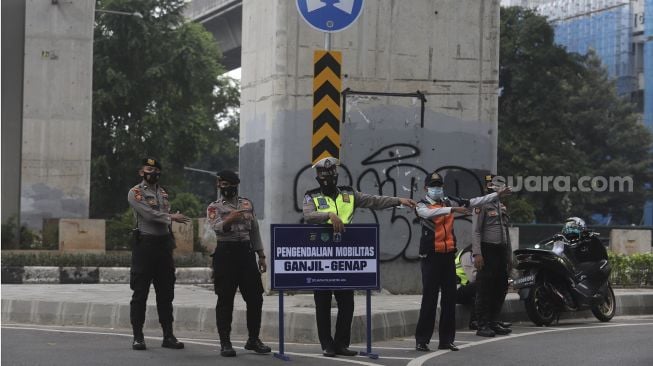 Polisi mengatur lalu lintas kendaraan di pos penerapan ganjil genap di Jalan HR Rasuna Said, Jakarta, Rabu (1/9/2021). [Suara.com/Angga Budhiyanto]