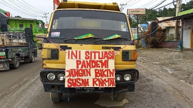 Salah satu truk dengan tulisan orasi saat unjuk rasa di Jalan Poros Samarinda-Bontang. [Suara.com/Apriskian Tauda Parulian]