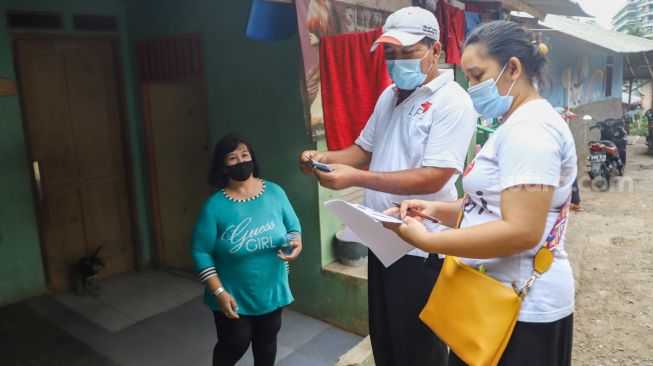 Petugas memberikan data kependudukan berupa KTP dan Kartu Keluarga ke warga Kebun Sayur di Ciracas, Jakarta Timur, Jumat (3/9/2021). [Suara.com/Alfian Winanto]