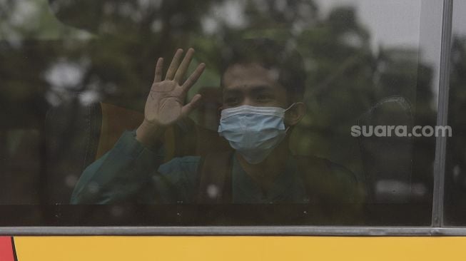 Pelajar melambaikan tangan saat menaiki Bus Sekolah Gratis usai mengikuti pembelajaran tatap muka (PTM) di SMK Negeri 15 Jakarta, Kebayoran Baru, Jakarta Selatan, Jumat (3/9/2021). [Suara.com/Angga Budhiyanto]