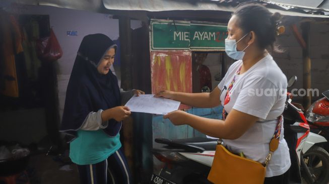 Petugas memberikan data kependudukan berupa KTP dan Kartu Keluarga ke warga Kebun Sayur di Ciracas, Jakarta Timur, Jumat (3/9/2021). [Suara.com/Alfian Winanto]