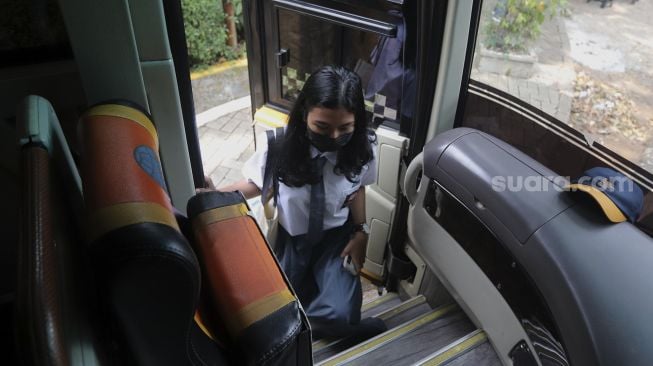 Pelajar menaiki Bus Sekolah Gratis usai mengikuti pembelajaran tatap muka (PTM) di SMK Negeri 15 Jakarta, Kebayoran Baru, Jakarta Selatan, Jumat (3/9/2021). [Suara.com/Angga Budhiyanto]