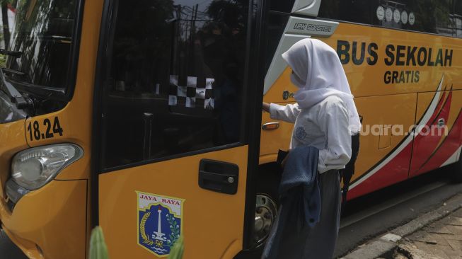 Pelajar menaiki Bus Sekolah Gratis usai mengikuti pembelajaran tatap muka (PTM) di SMK Negeri 15 Jakarta, Kebayoran Baru, Jakarta Selatan, Jumat (3/9/2021). [Suara.com/Angga Budhiyanto]